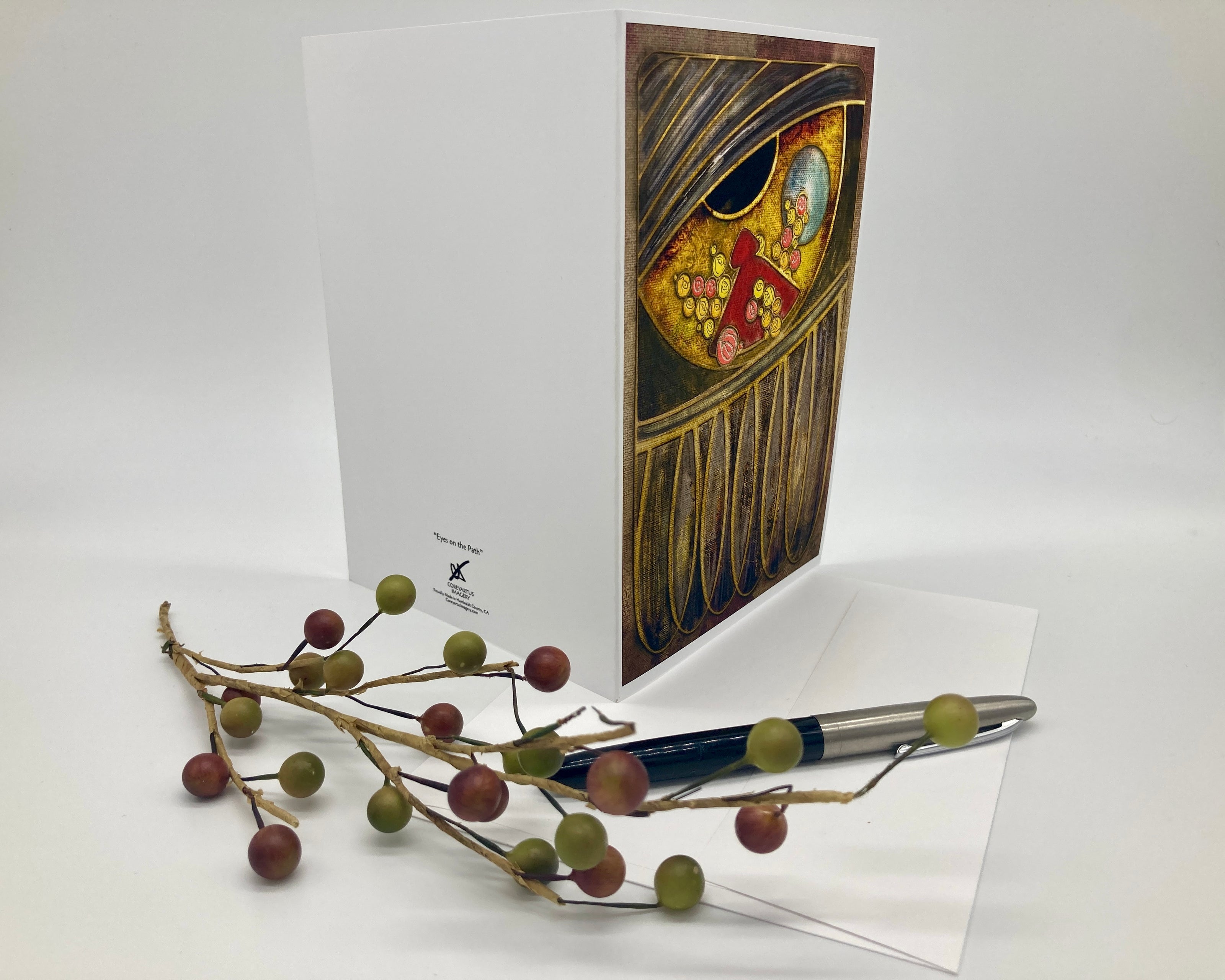 Decorative greeting card with artistic design, pen, and decorative branch on a white background