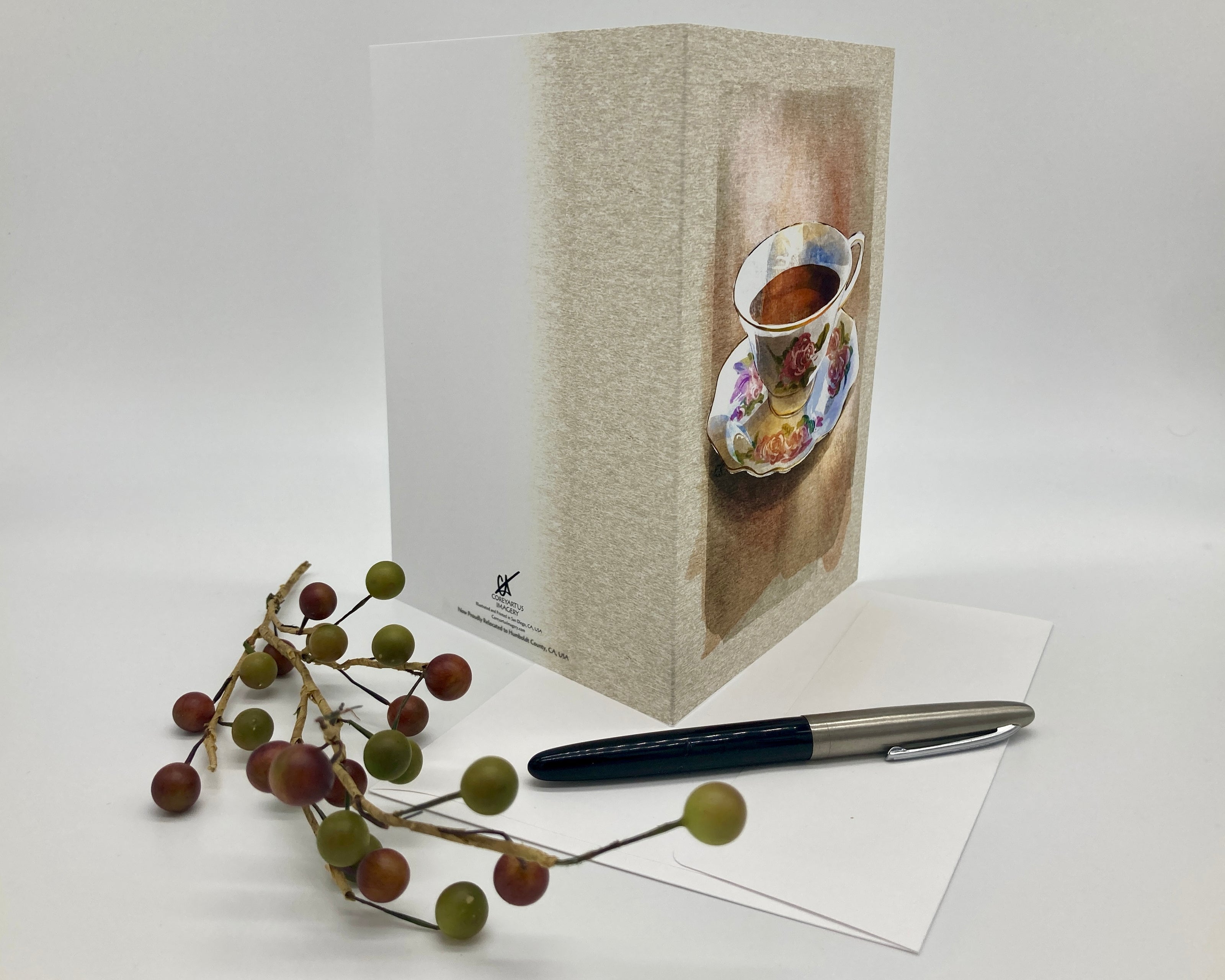 Greeting card with teacup design, pen, and decorative branches on a white background