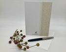 Back of a greeting card displayed with a pen, and decorative branch on a white surface