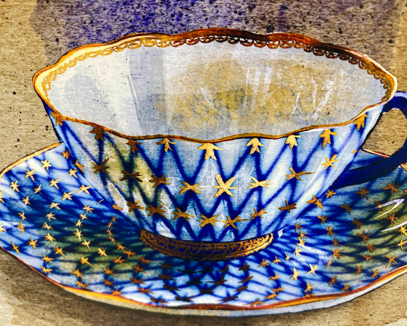 Decorative ceramic teacup and saucer with blue and gold pattern on a wooden surface