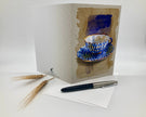 Greeting card with a blue teacup design, pen, and wheat stalks on a white background