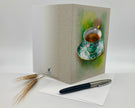 Greeting card with a tea cup design on a white surface with a pen and paper.