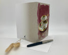 Greeting card with teacup design on a white surface with a pen and decorative item.