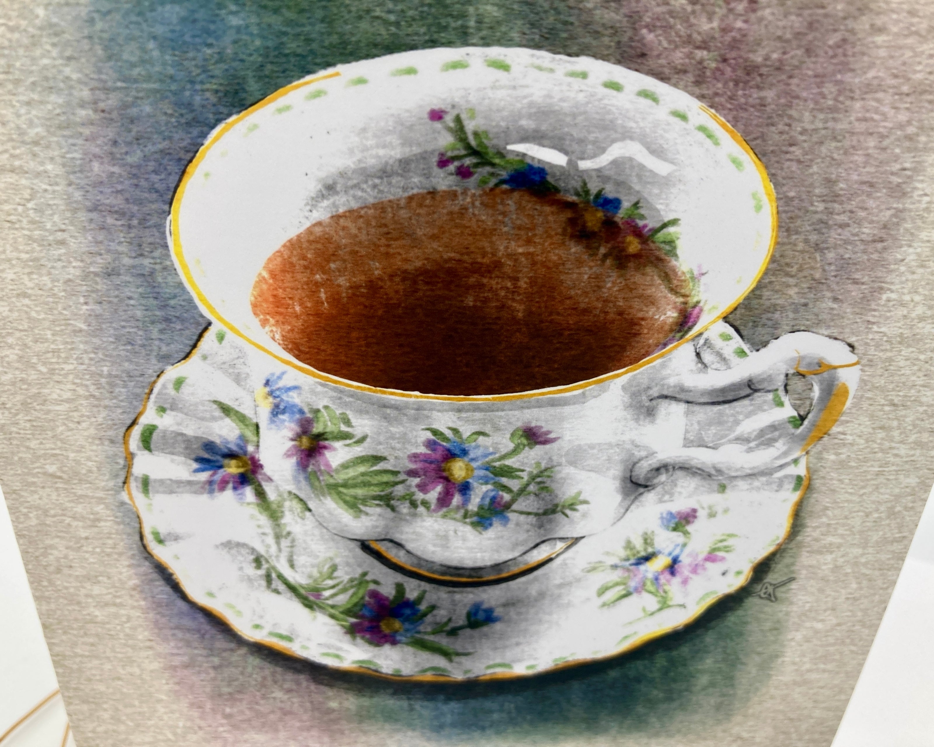 Teacup with floral design on a saucer containing a dark liquid, placed on a textured surface.