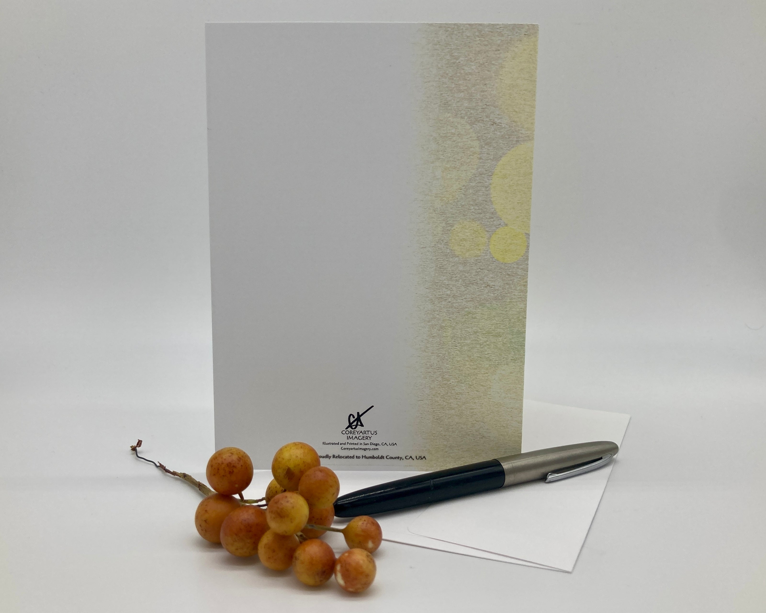 Back of greeting card displayed with a pen and grapes on a white background