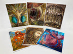 Set of six artistic greeting cards with various designs on a white background