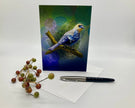 Greeting card with a bird illustration on a white surface with berries and a pen.