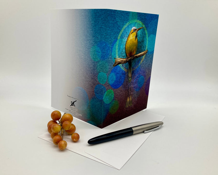 Greeting card with a bird design on a white surface with a pen and grapes.