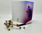Greeting card with a colorful bird design on a white surface with a pen and decorative branches.