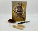 Greeting card with a bird illustration on a branch, accompanied by a pen and decorative items.