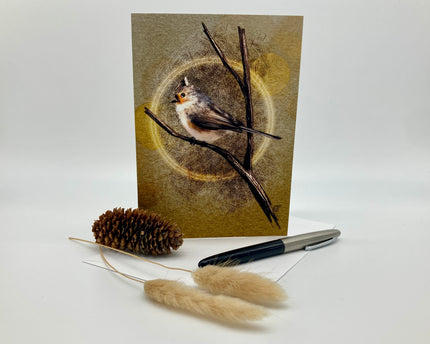Greeting card with a bird illustration on a branch, accompanied by a pen and decorative items.