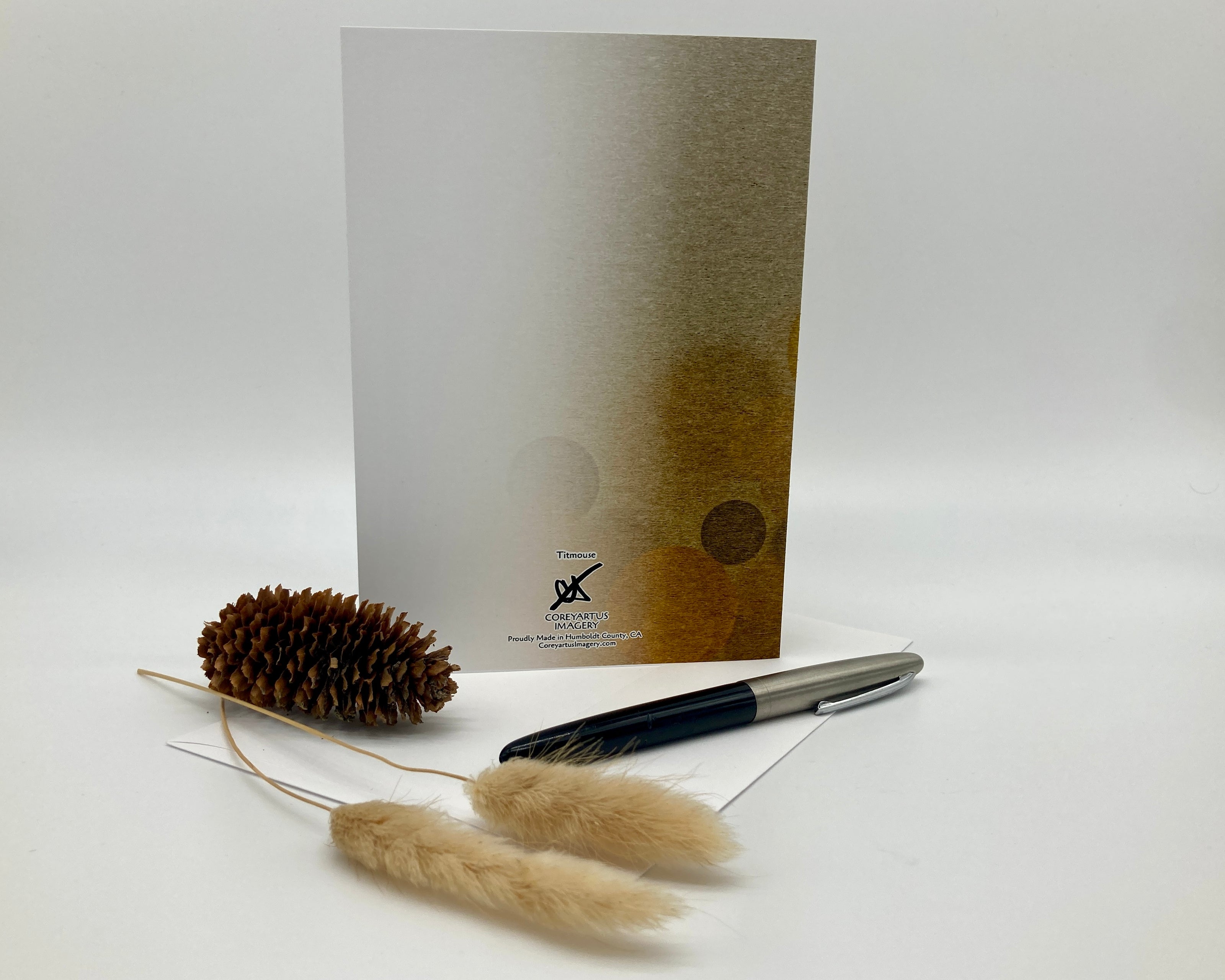 Pen, decorative elements, and a card with a brand logo on a white background