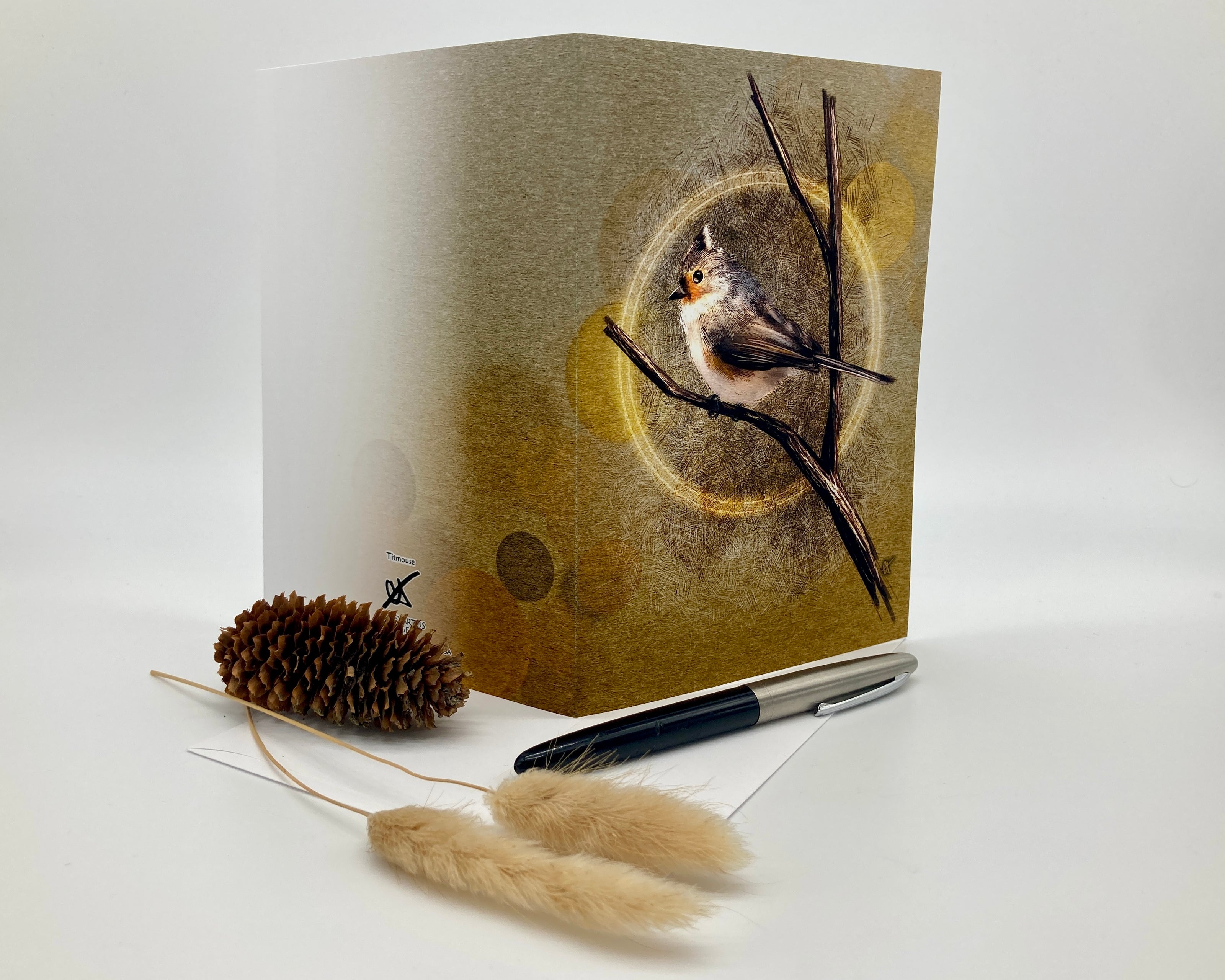 Greeting card with a bird design on a branch, accompanied by a pen and decorative elements.