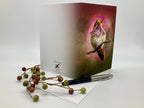 Greeting card with a bird design on a white surface with berries and a pen.