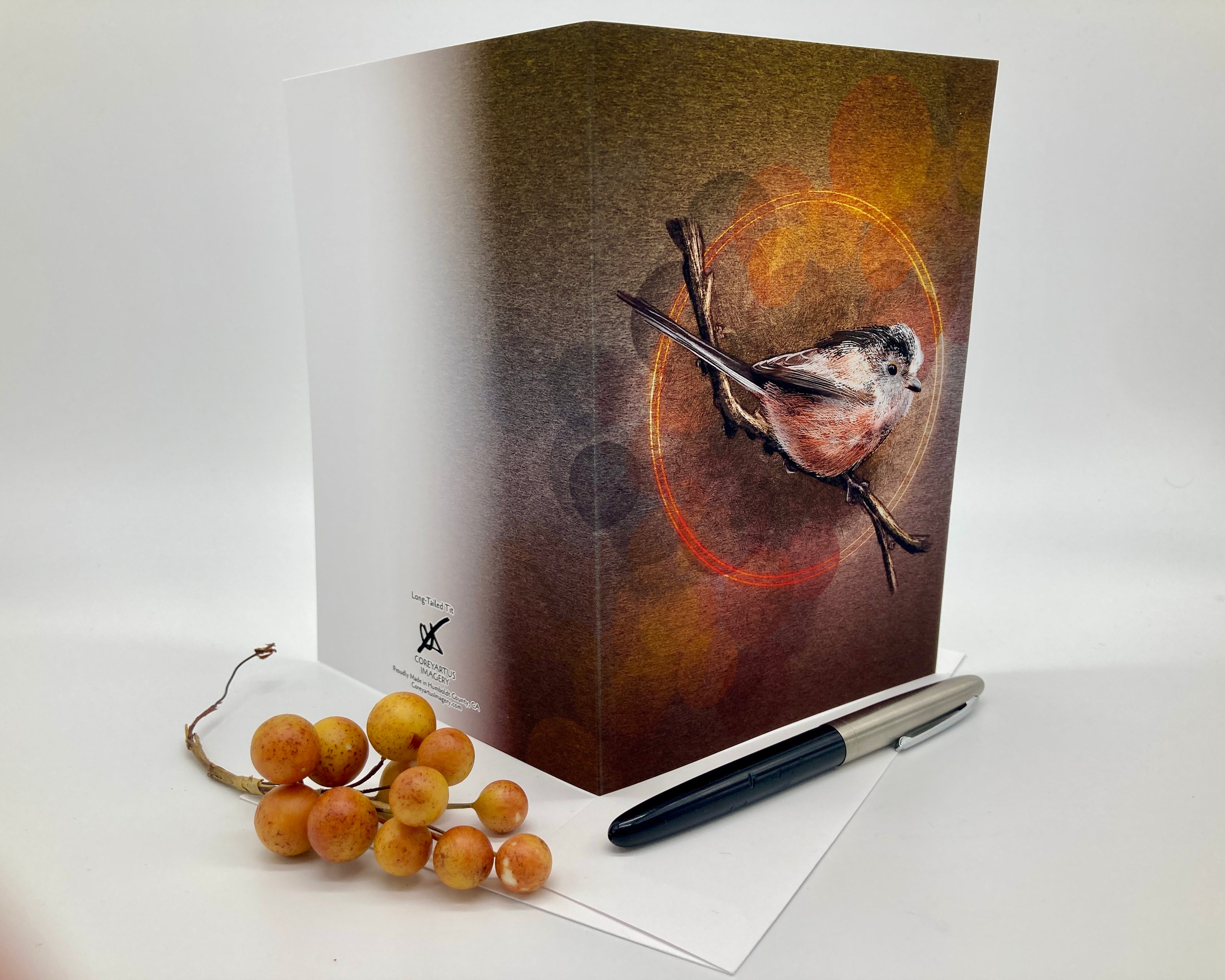 Greeting card with bird illustration on a white surface with berries and pen