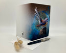 Greeting card with a bird design on a white surface with a pen and decorative item.