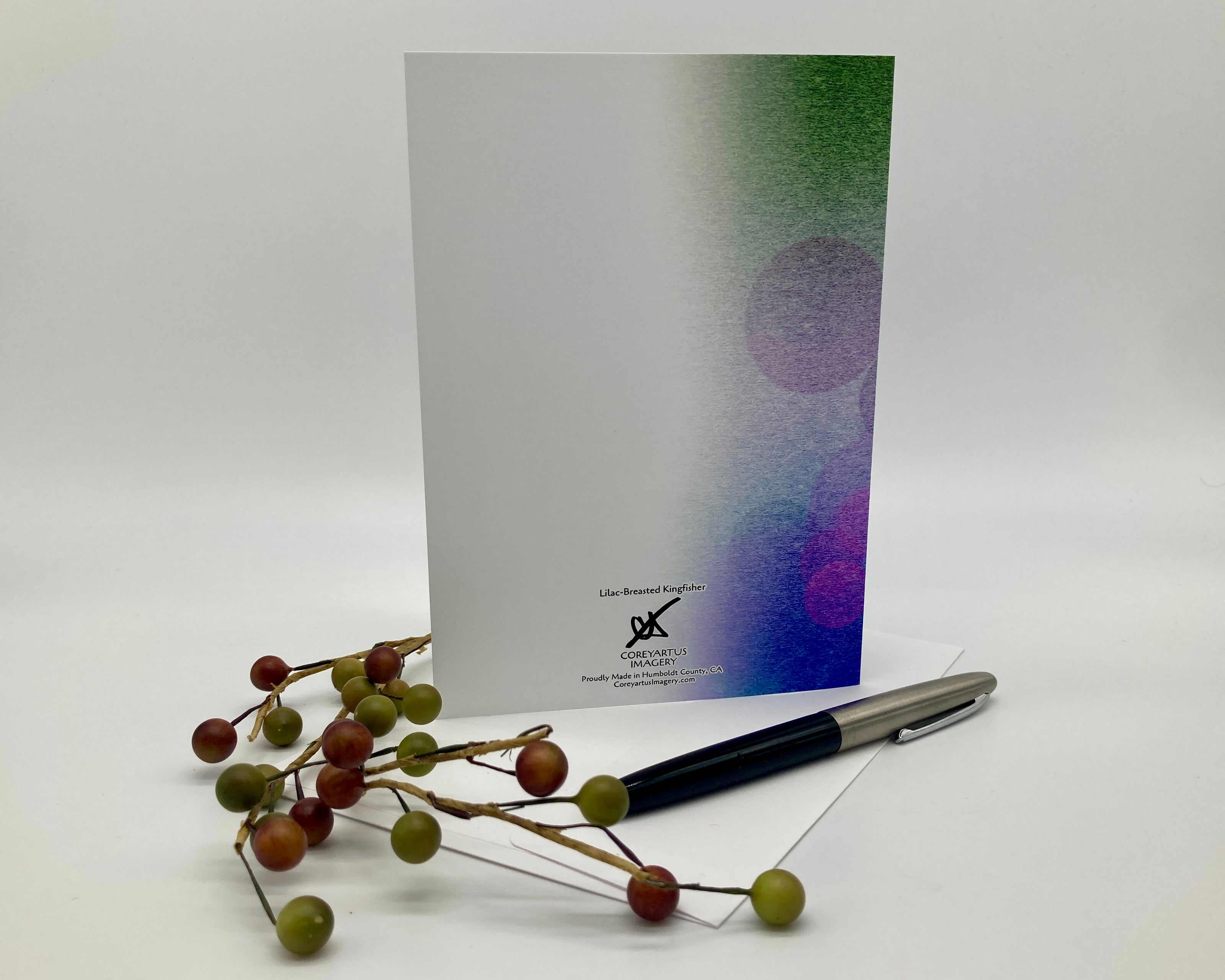 Back of a greeting card displayed with a pen and a sprig of fake berries.