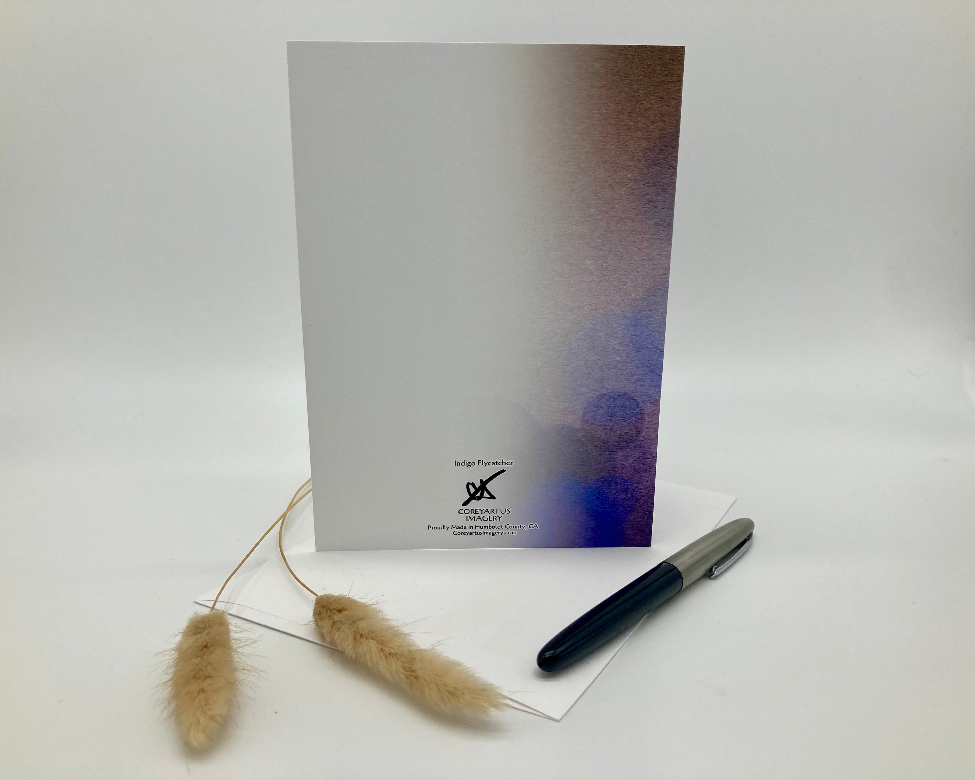 Back of a greeting card with a pen and decorative item on a white background