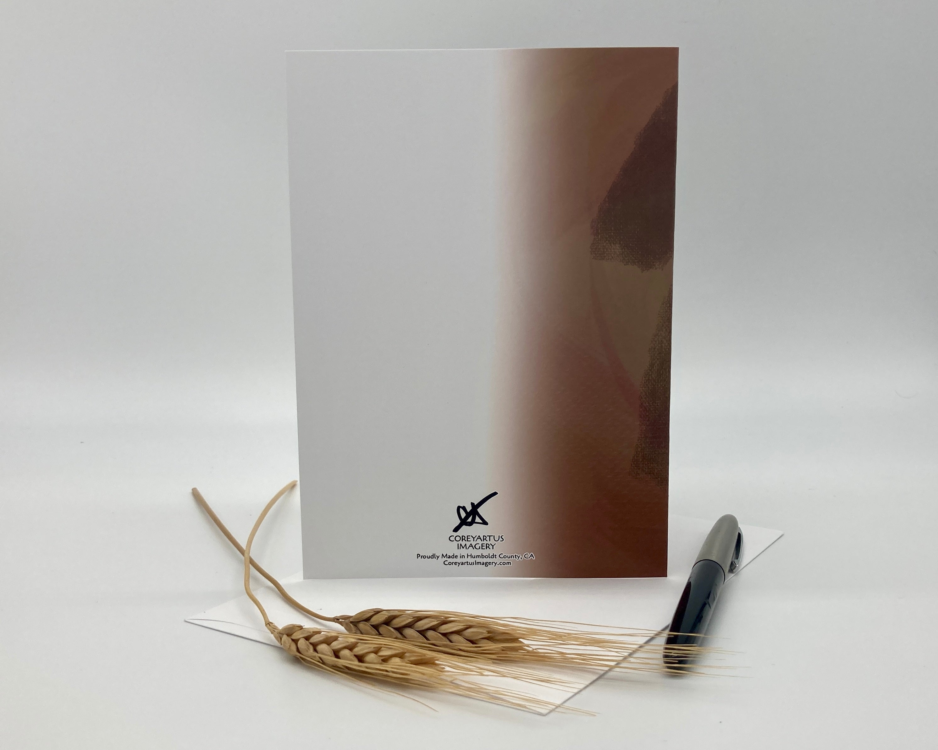 Back of a greeting card, displayed with a pen and wheat stalks on a white background