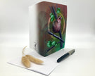 Open greeting card with bird illustration on cover, pen, and feather on white background