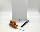White card with a logo, pen, and small fruit on a white background