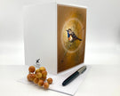 Greeting card with bird illustration on a white surface with fruits and a pen.