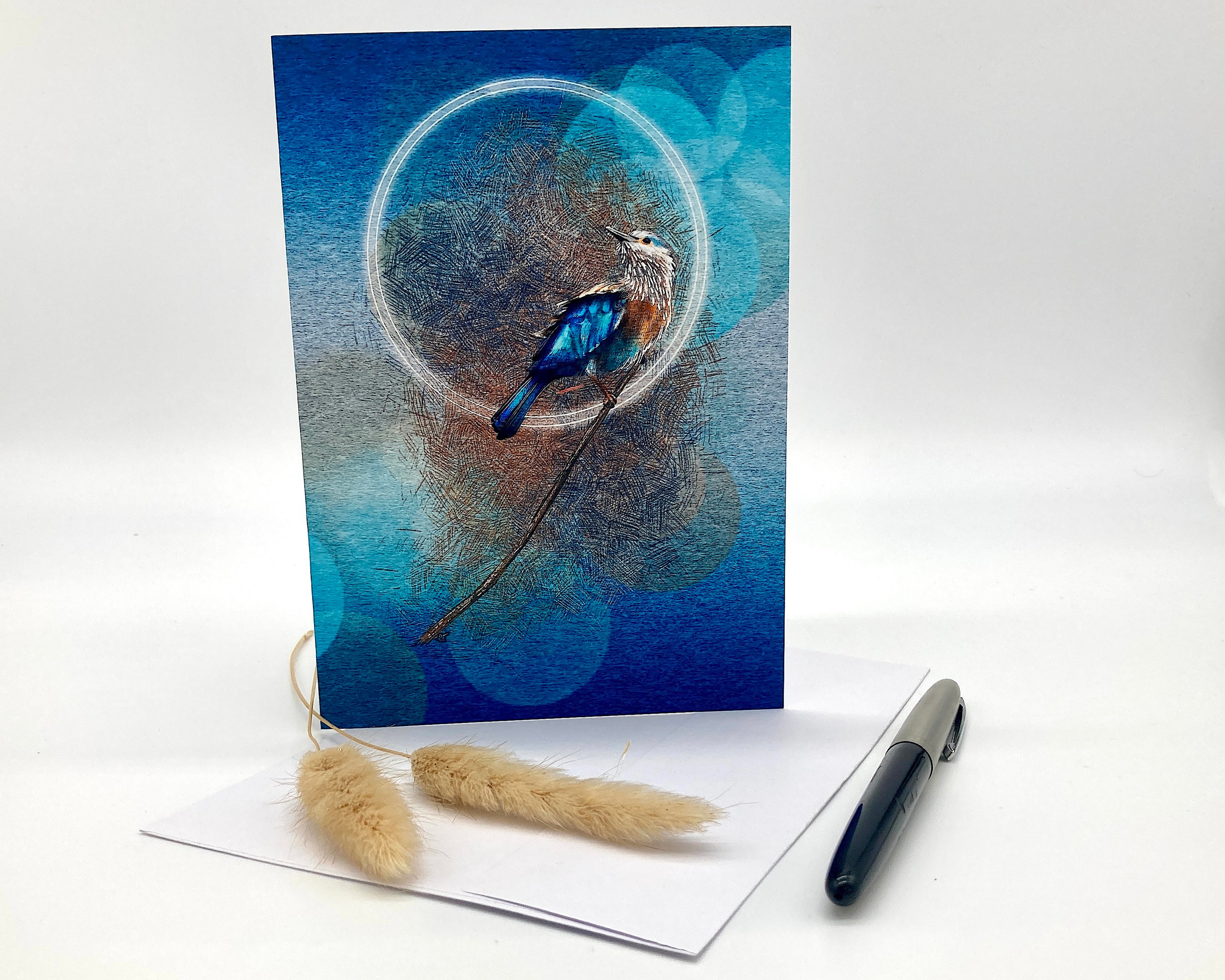 Greeting card with a blue bird design on a white surface with a pen and decorative elements.