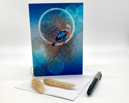 Greeting card with a blue bird design on a white surface with a pen and decorative elements.
