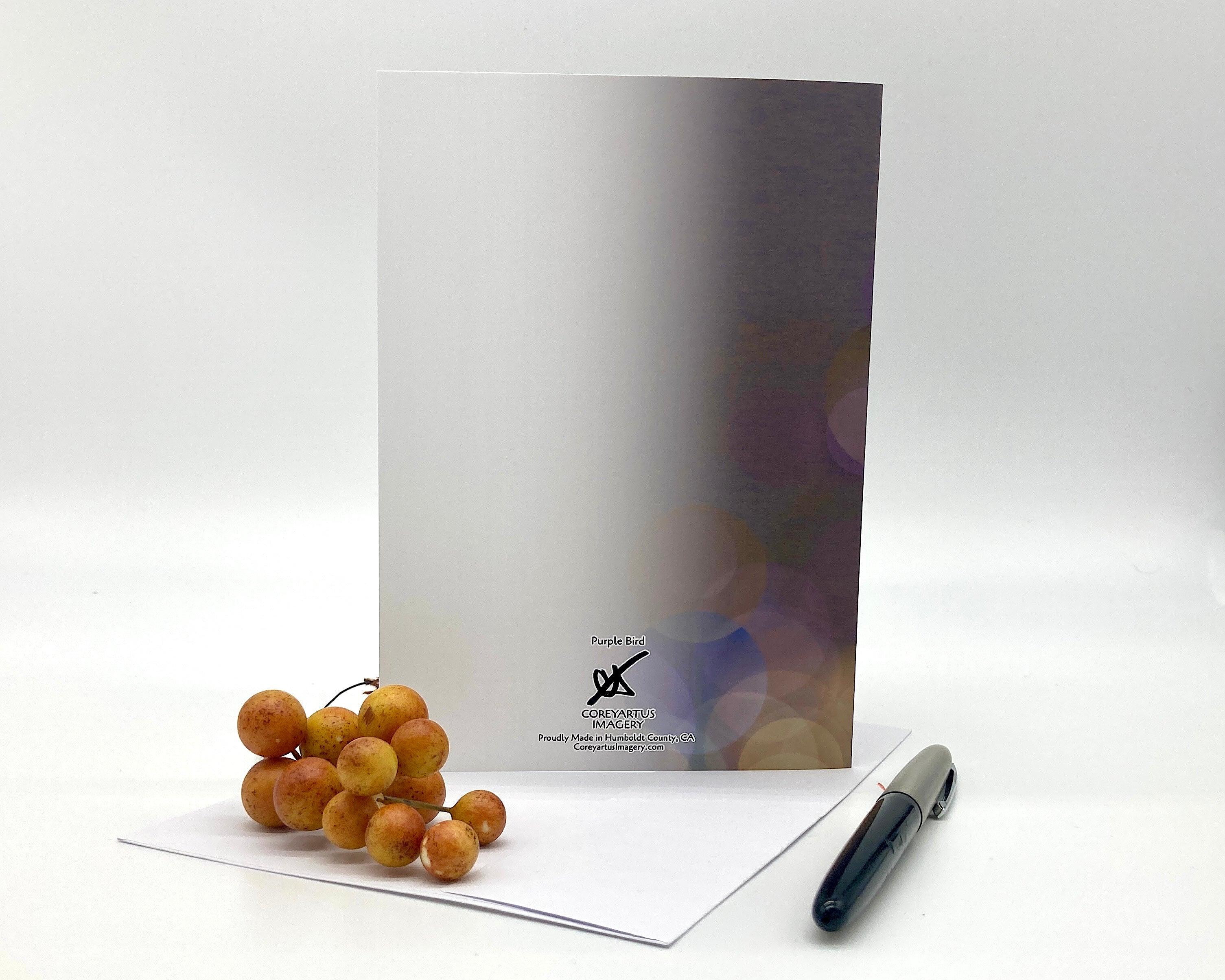 Back of a greeting card displayed on a white surface with berries and a pen