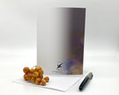 Back of a greeting card displayed on a white surface with berries and a pen