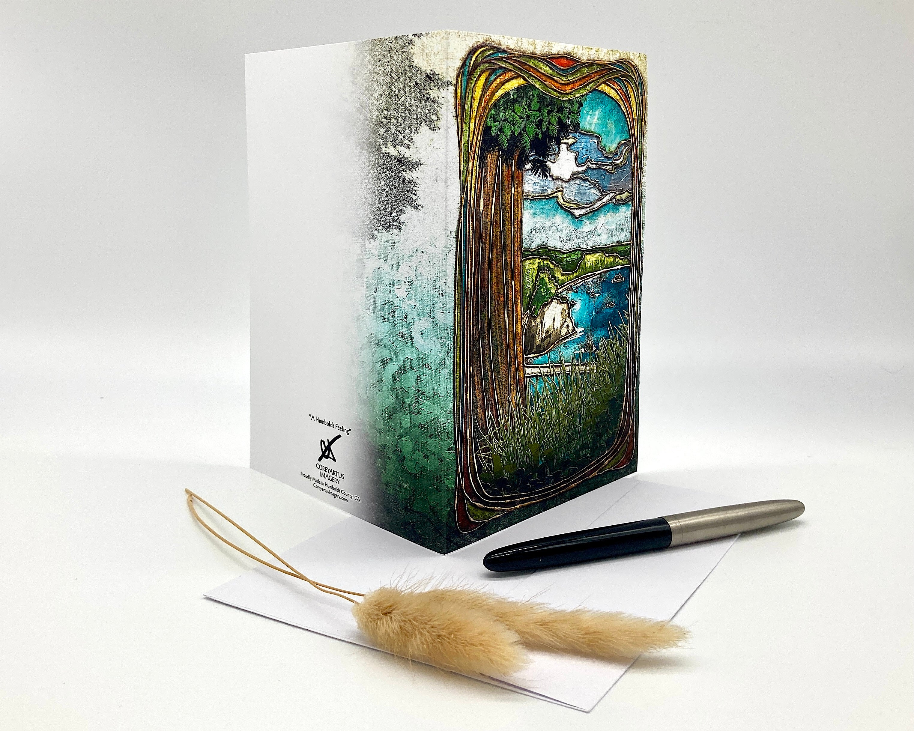 Decorative notebook with artistic cover design, pen, and feather on a white background