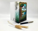 Decorative notebook with artistic cover design, pen, and feather on a white background