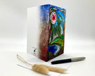 Decorative notebook with artistic cover design, pen, and feather on a white background