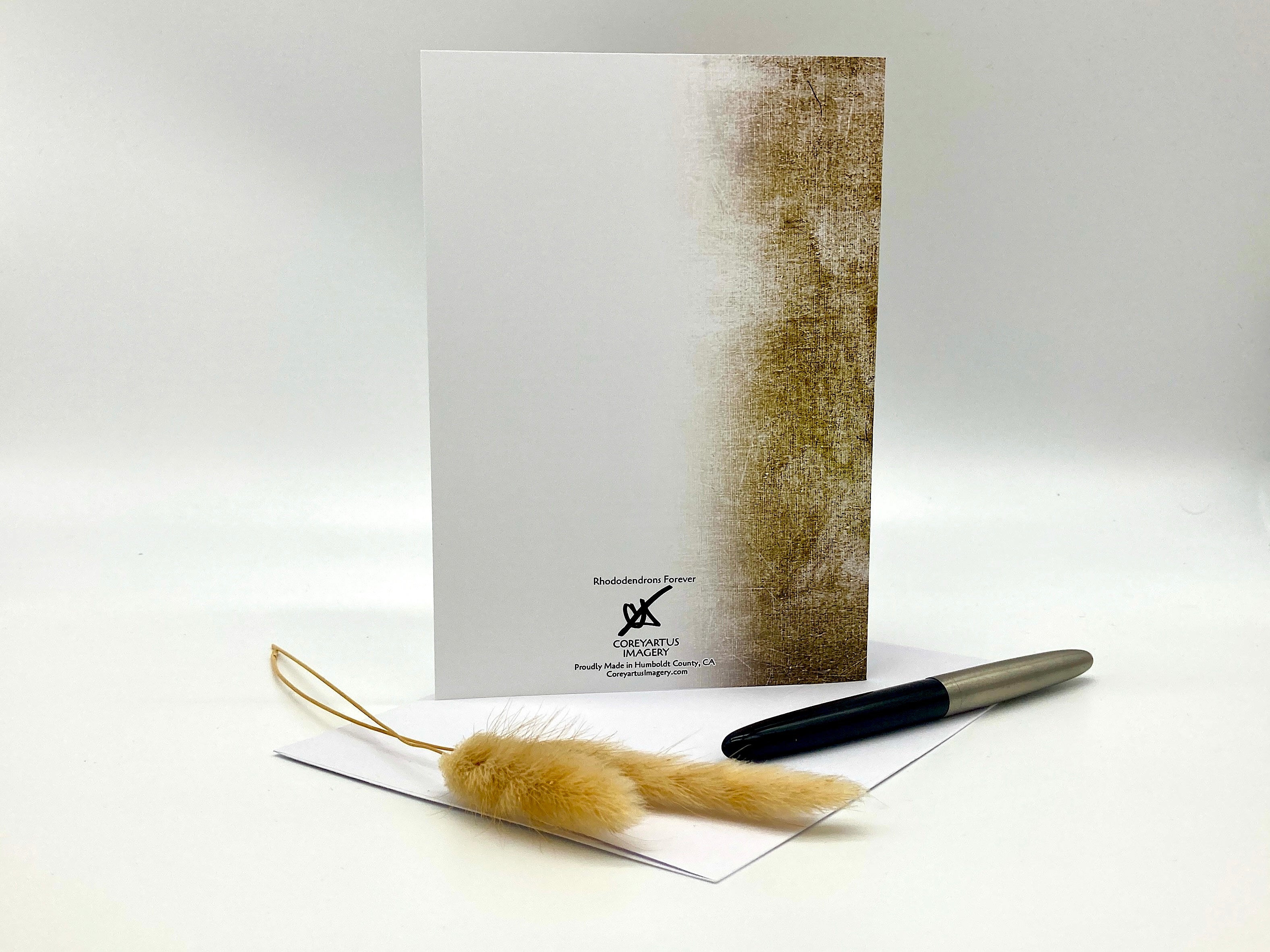 Greeting card with textured design, feather, and pen on a white background