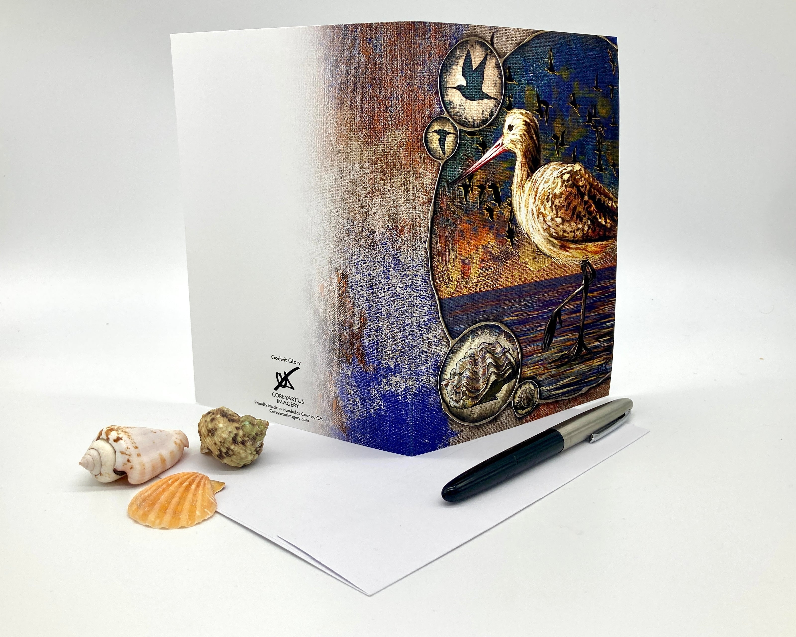 Greeting card with a bird design on a white surface with shells and a pen.