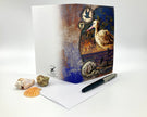 Greeting card with a bird design on a white surface with shells and a pen.