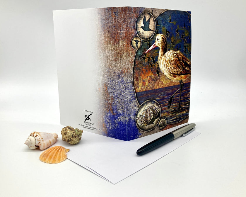 Greeting card with a bird design on a white surface with shells and a pen.