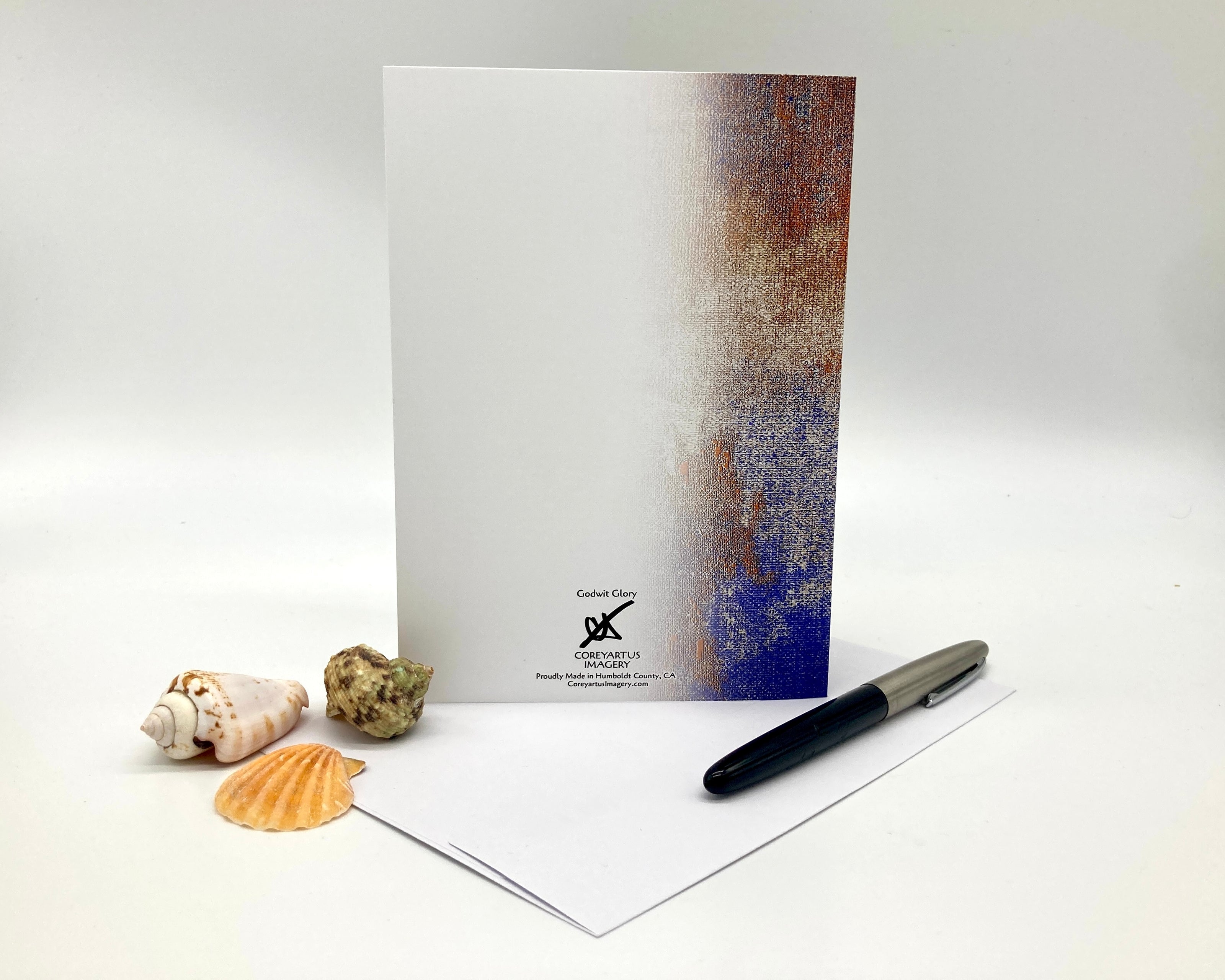 Notebook with a textured cover, pen, and seashells on a white background