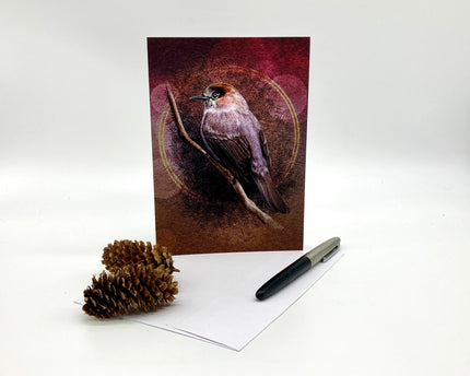 Greeting card with bird design, pen, and pine cone on a white background