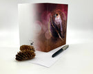 Greeting card with bird design, pen, and pine cone on a white background