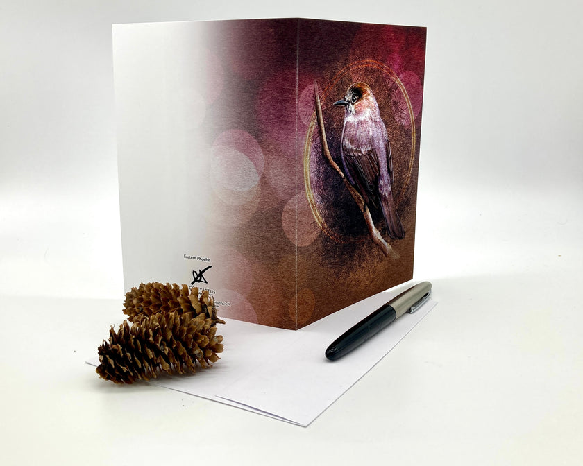 Greeting card with bird design, pen, and pine cone on a white background