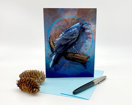 Greeting card with a blue bird design, pen, and pine cone on a white background