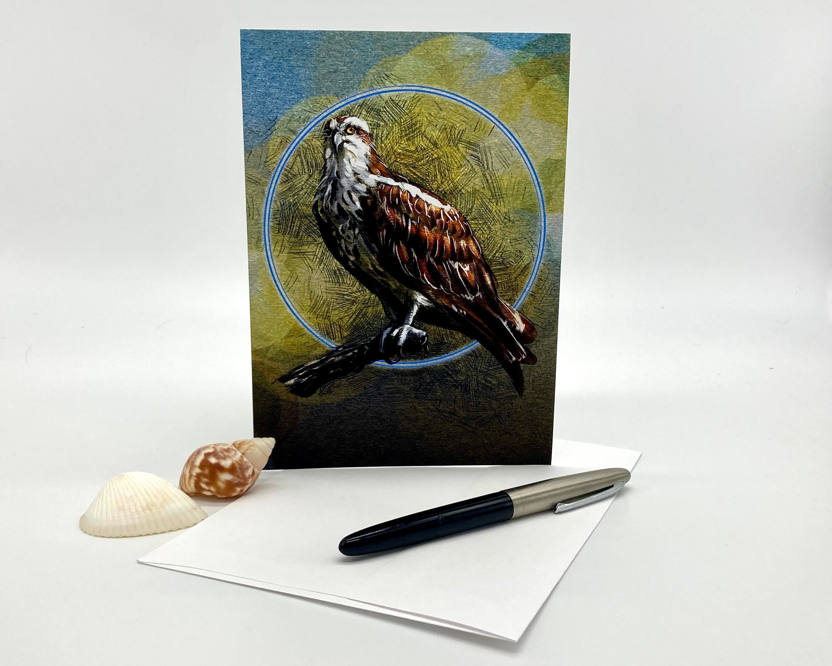 Greeting card with a bird design on a white surface with a pen and shell.