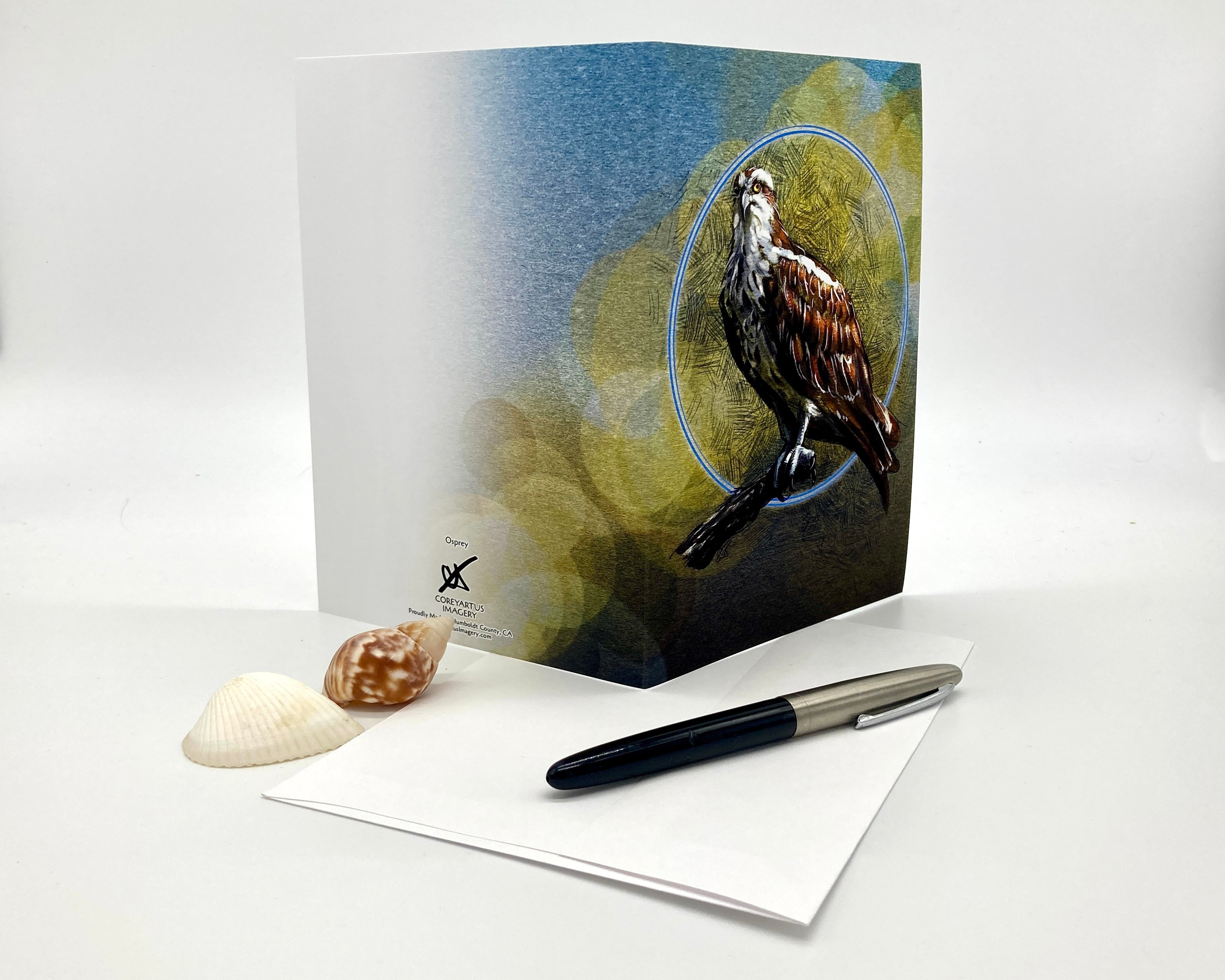 Greeting card with a bird design on a white surface with a pen and shell.