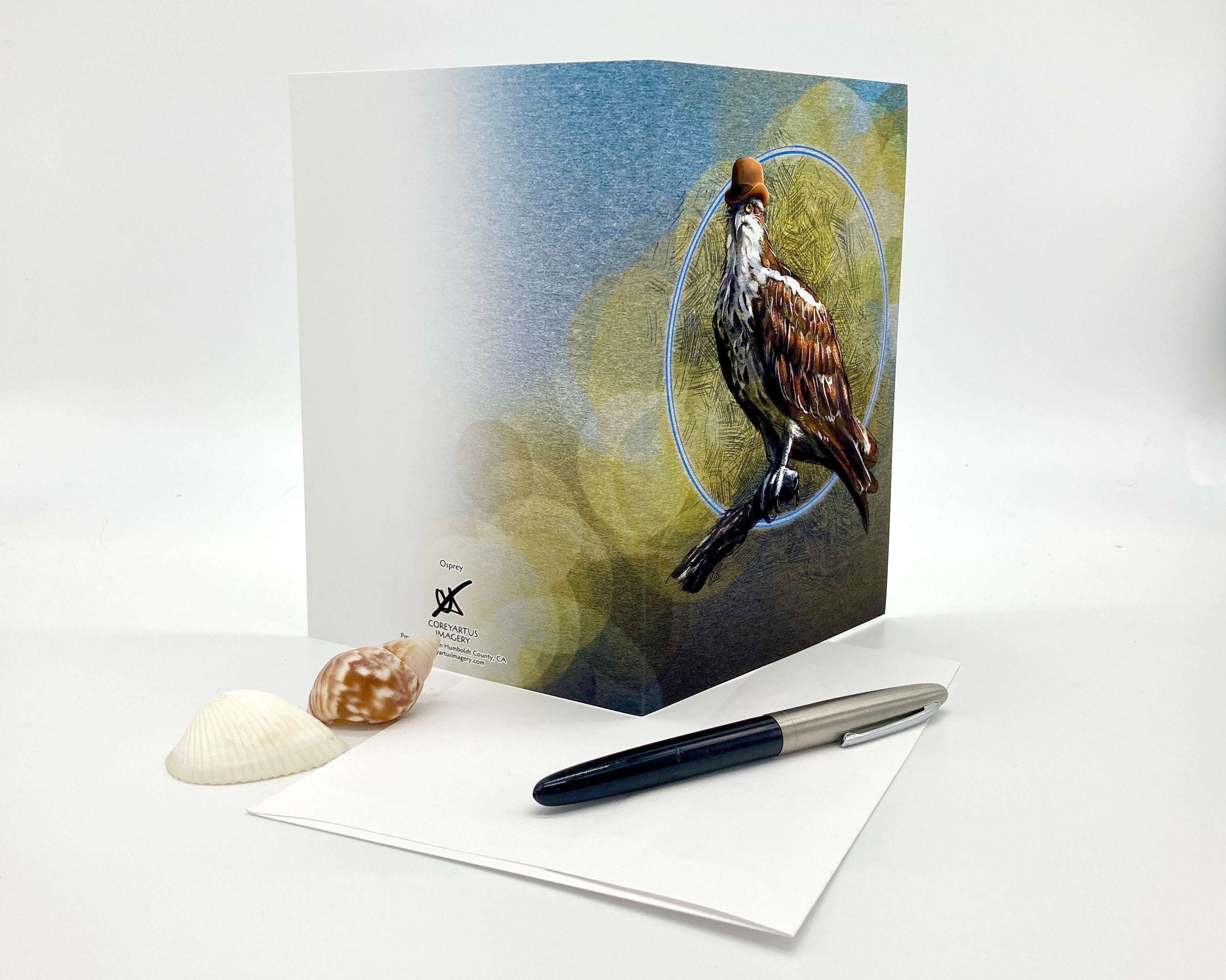 Greeting card with a bird design on a white surface with a pen and shell.