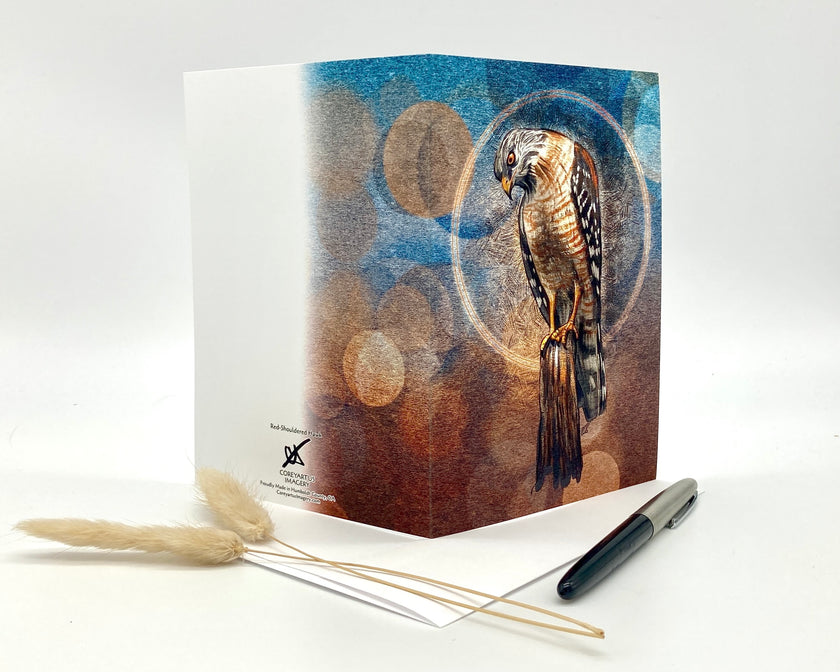 Greeting card with a bird design on a white surface with a pen and dried plants.