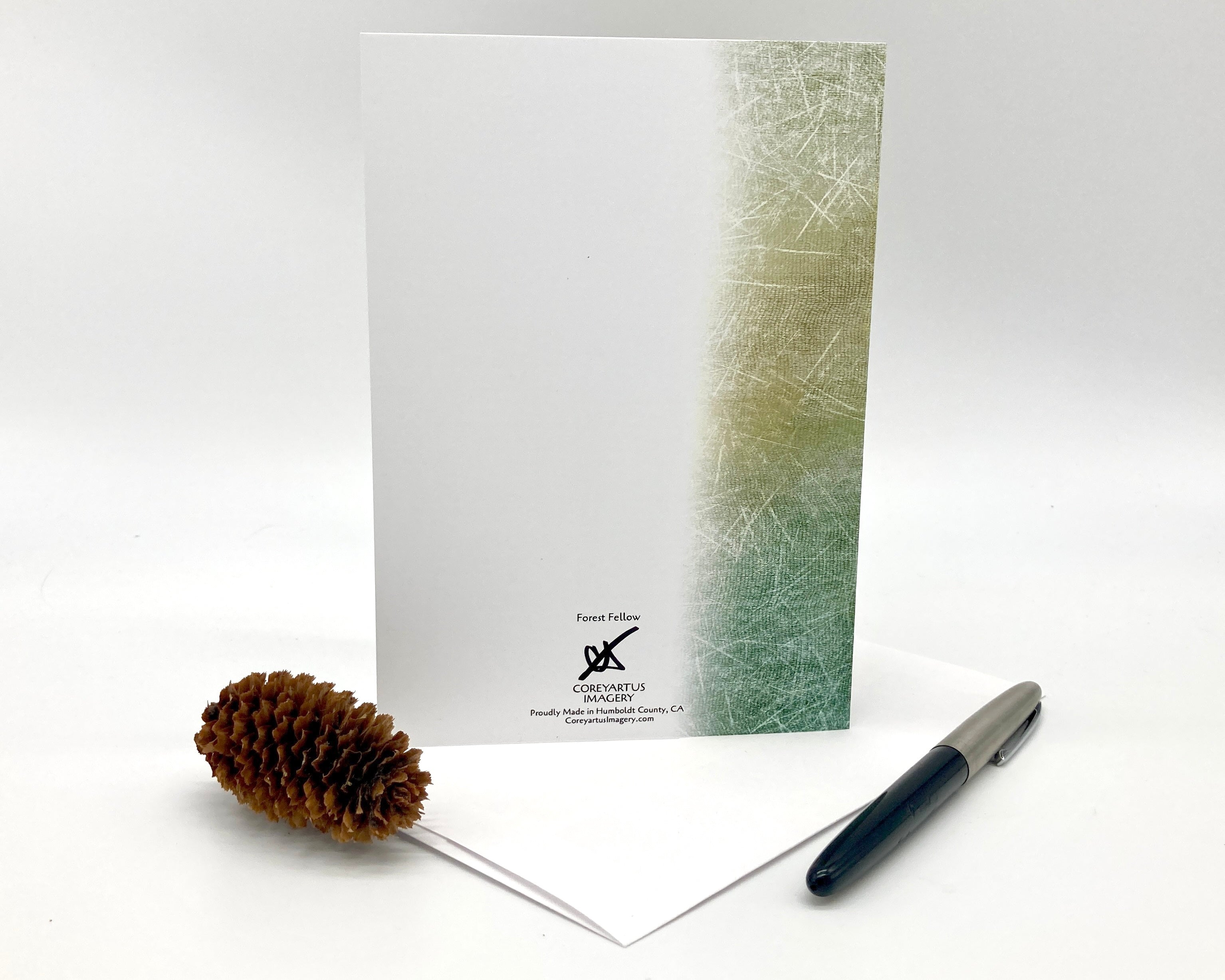 Notebook with a textured cover, pine cone, and pen on a white background