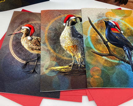 Three Christmas-themed greeting cards with birds wearing Santa hats on a white surface.