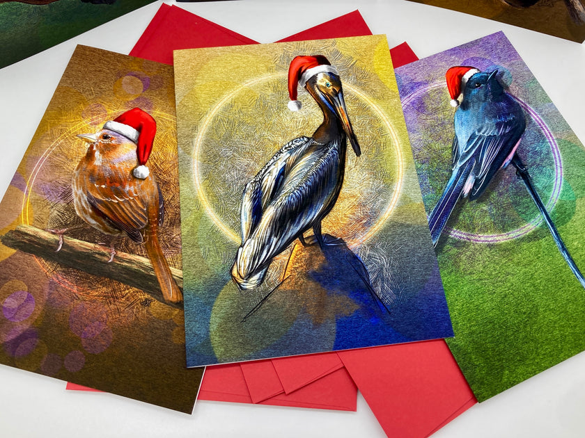 Three Christmas-themed greeting cards with birds wearing Santa hats on a white surface.
