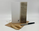 Greeting card with textured design, pen, and dried plants on a white background